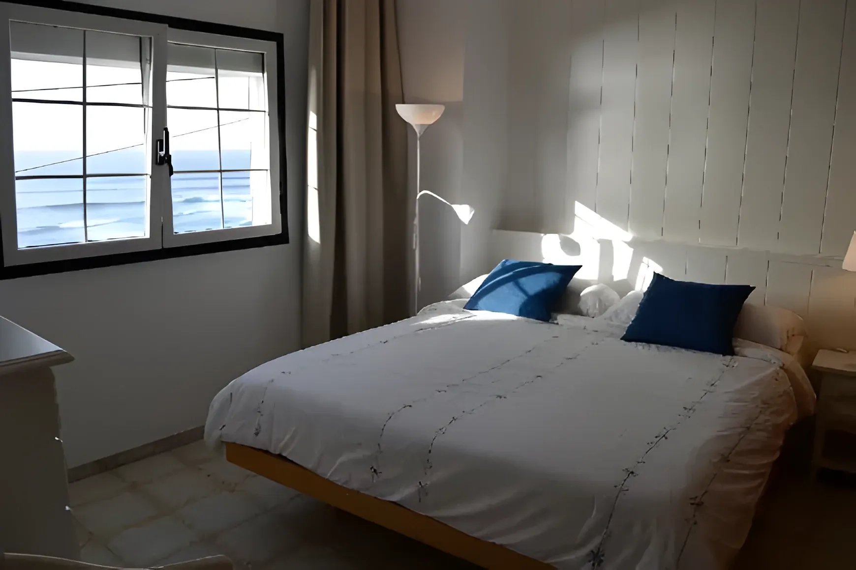 Dormitorio con cama doble y cojines azules