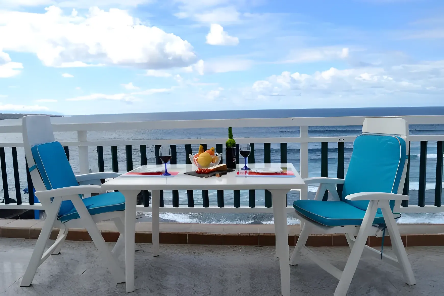 Comedor exterior con sillas azules y vistas al Atlántico