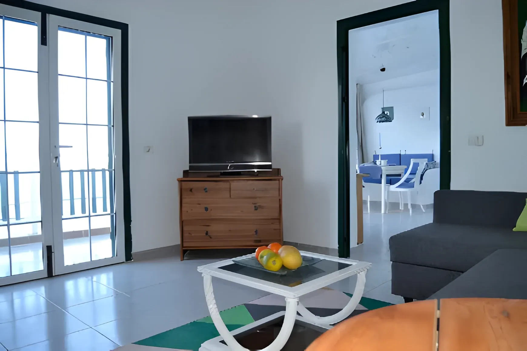 Salón con sofá, televisión y salida a la terraza